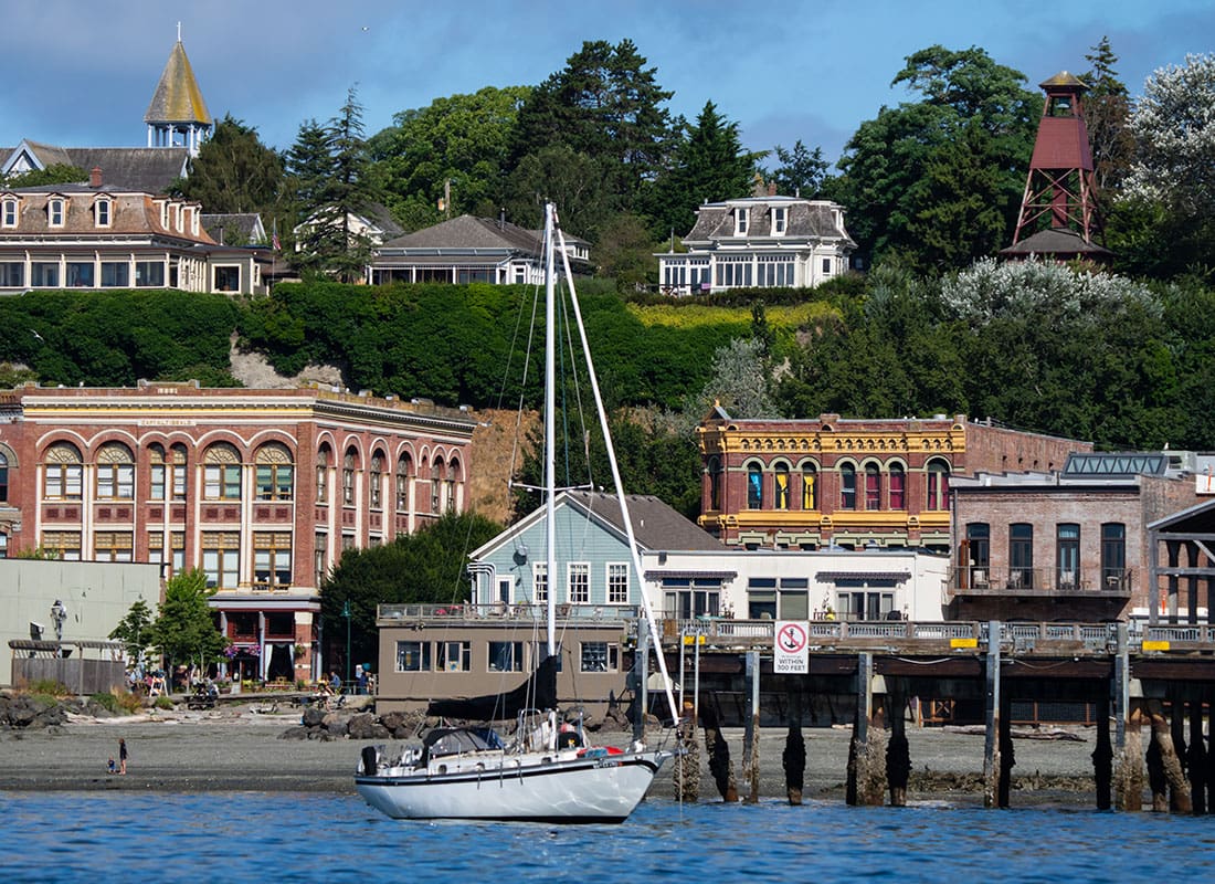 Port Townsend, WA - White Boat by the Shore with Historical Buildings and Small Businesses in Port Townsend Washington on a Sunny Day